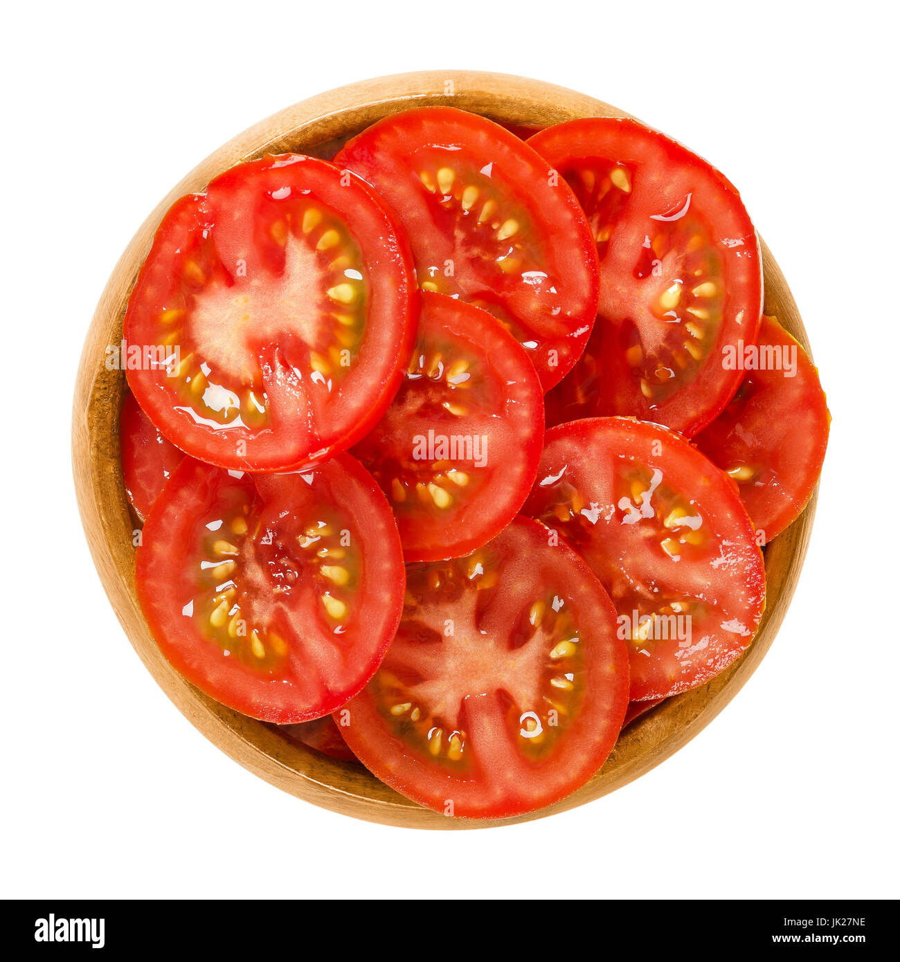 Tomato slices in wooden bowl. Edible ripe and raw fruit of Solanum lycopersicum with red color, cut into thin slivers. Isolated macro food photo. Stock Photo