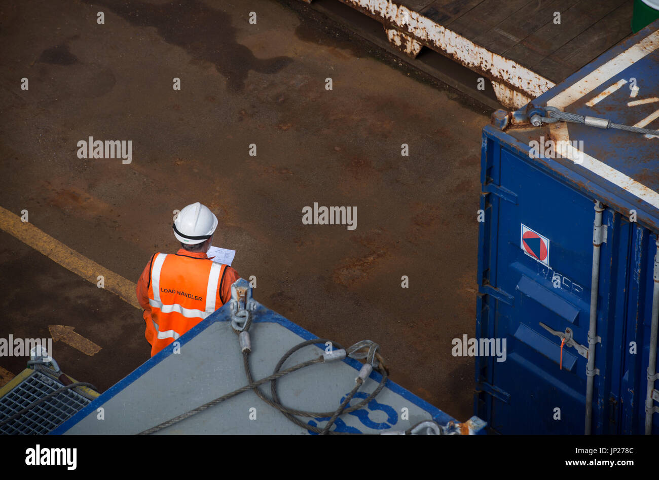 Offshore materials coordinator (store man) reading the manifest whilst wearing orange coveralls / overalls. credit: LEE RAMSDEN / ALAMY Stock Photo