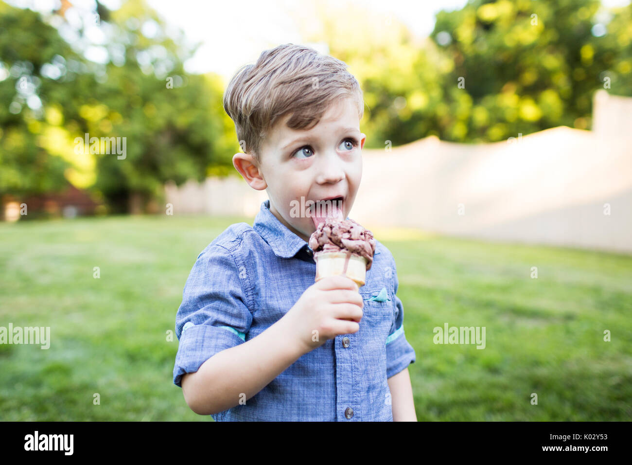 Preschool boy eating ice cream cone in summer yard Stock Photo