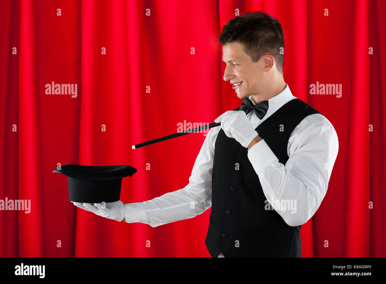 Young Happy Magician With Magic Wand And Black Hat Stock Photo