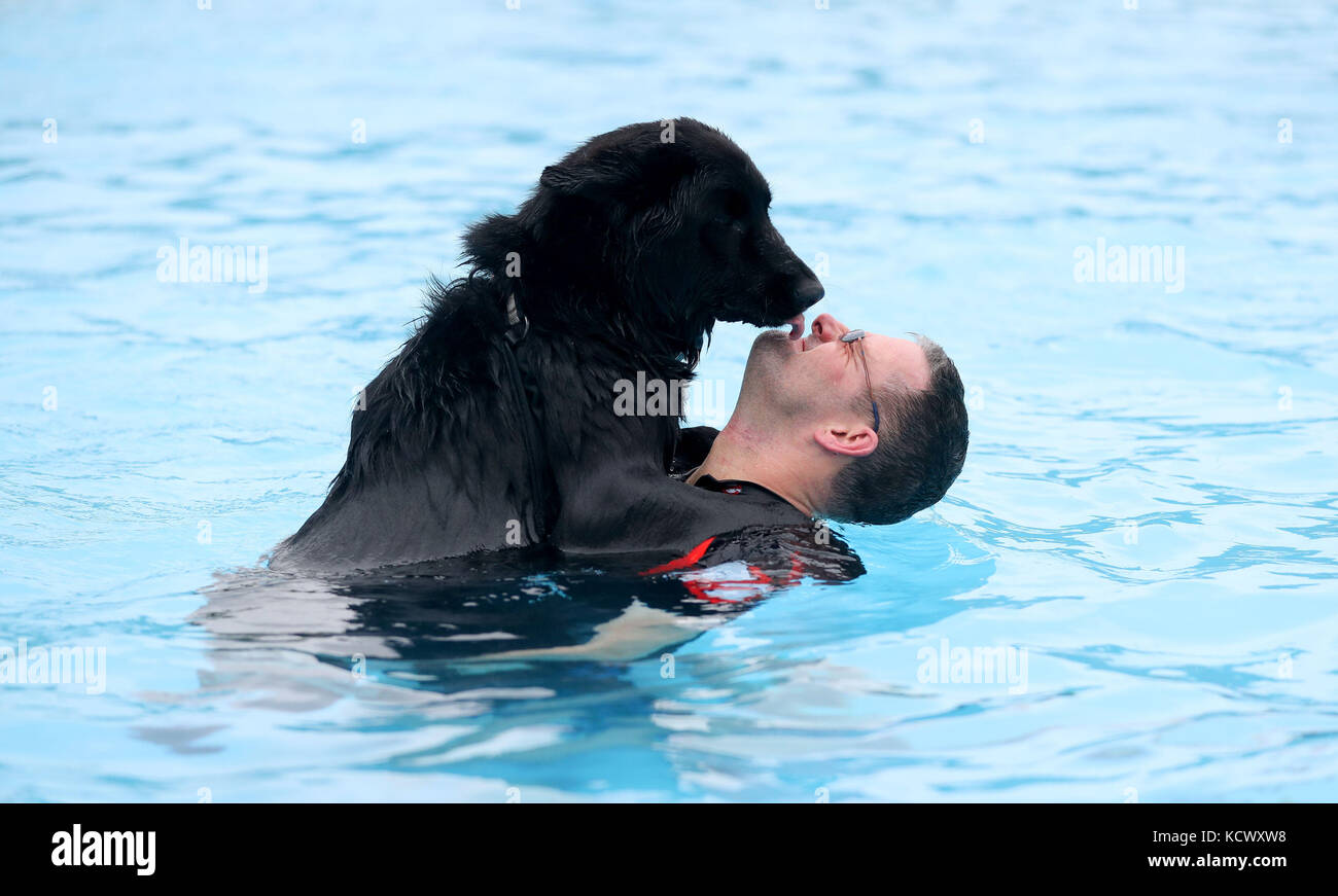 Chris Heath from Crawley swims with his German shepherd husky cross dog Pepsi at Saltdean Lido in the Oval Park, Saltdean, as the lido has invited dogs to enjoy the facility before it closes for the year. Stock Photo