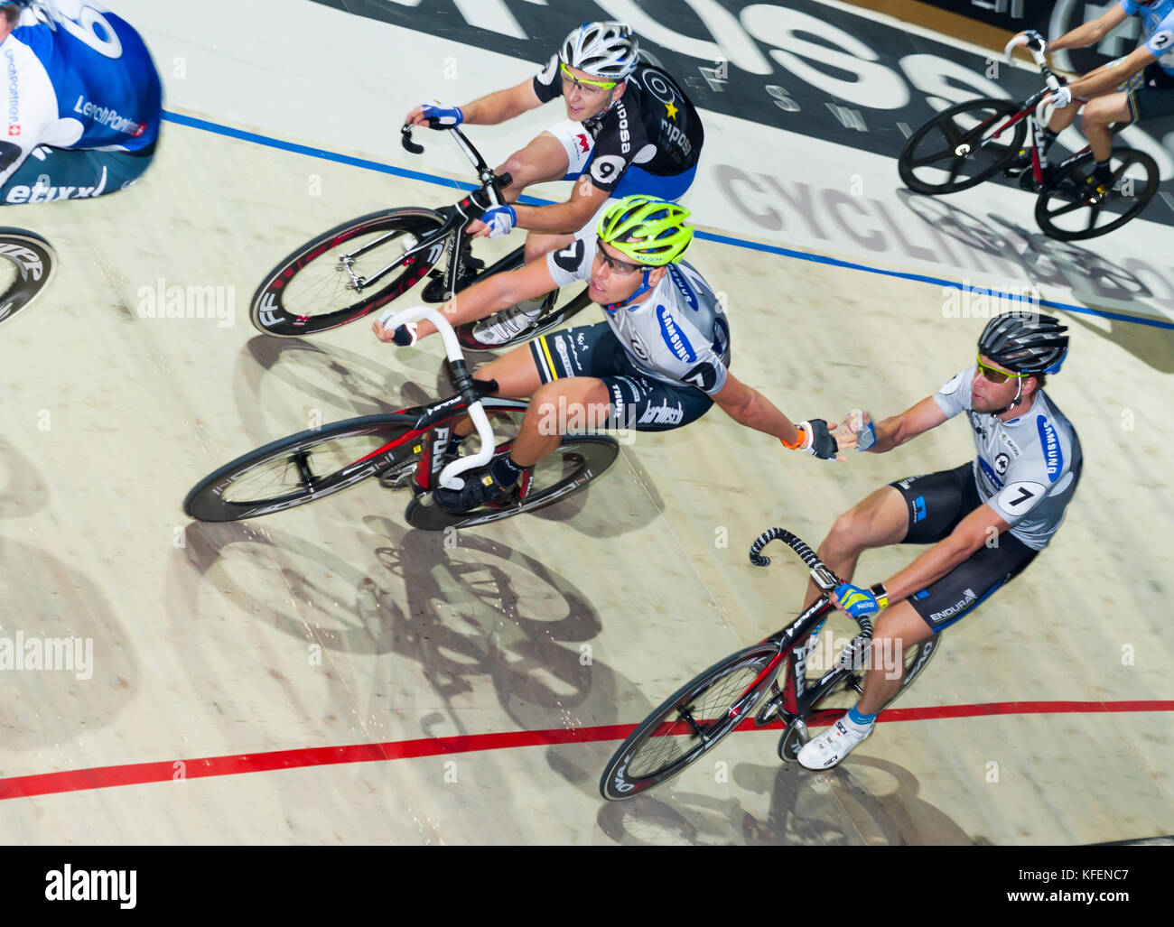 Zurich, Switzerland - 28 Nov 2013: German pro bicycle racer Leif Lamparter (right) hands over to his teammate Roger Kluge (yellow helmet) at the 2013 six day cycle race in Zurich's Hallenstadion. Following in black Kenny De Ketele (BEL). Stock Photo