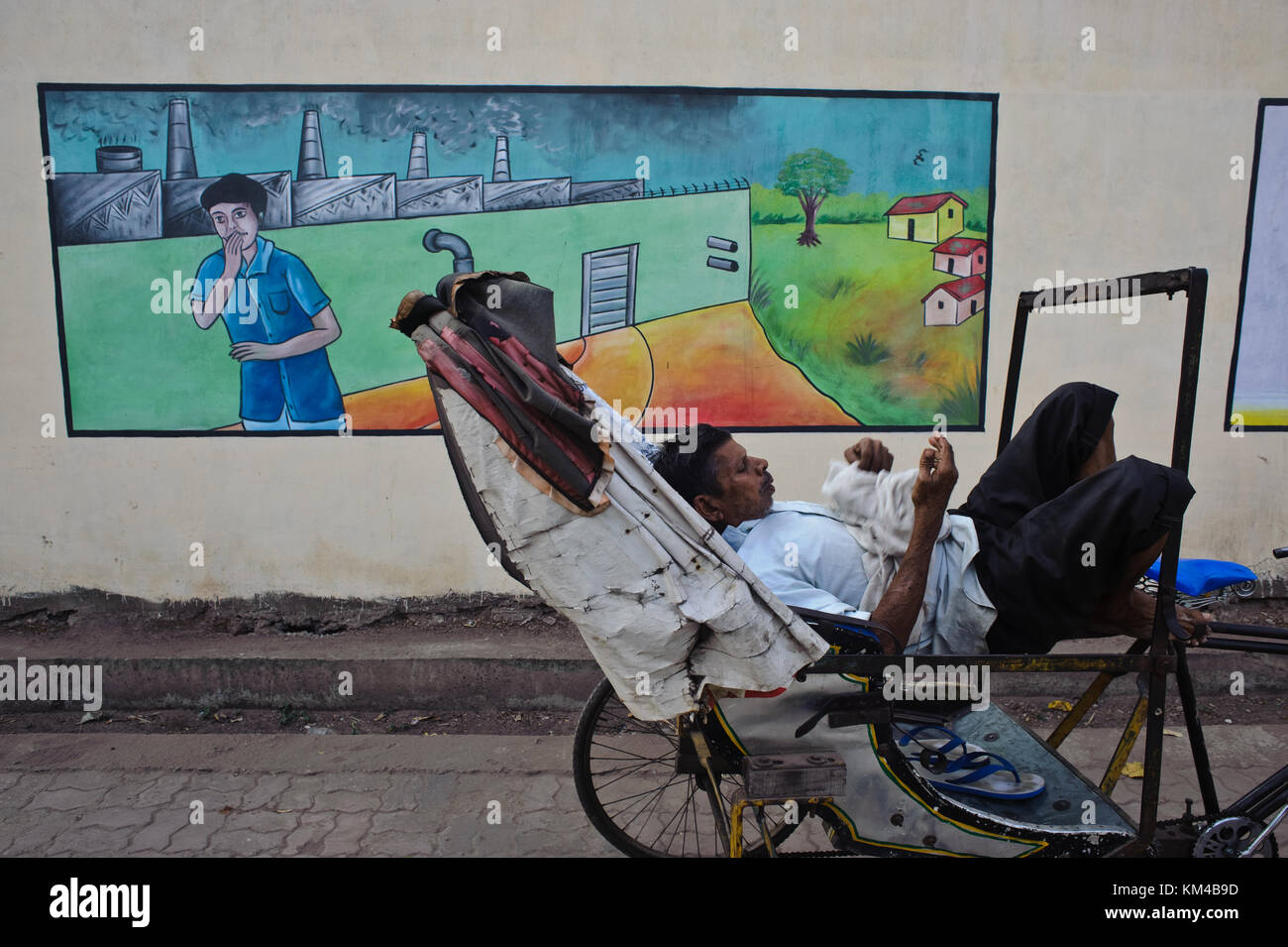 Anti pollution mural painting + cycle rickshaw puller taking rest ( India) Stock Photo