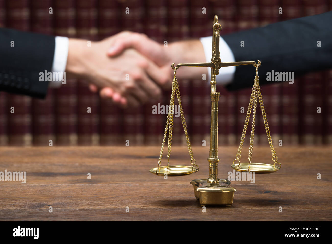 Justice Scale On Table With Judge And Client Shaking Hands Stock Photo