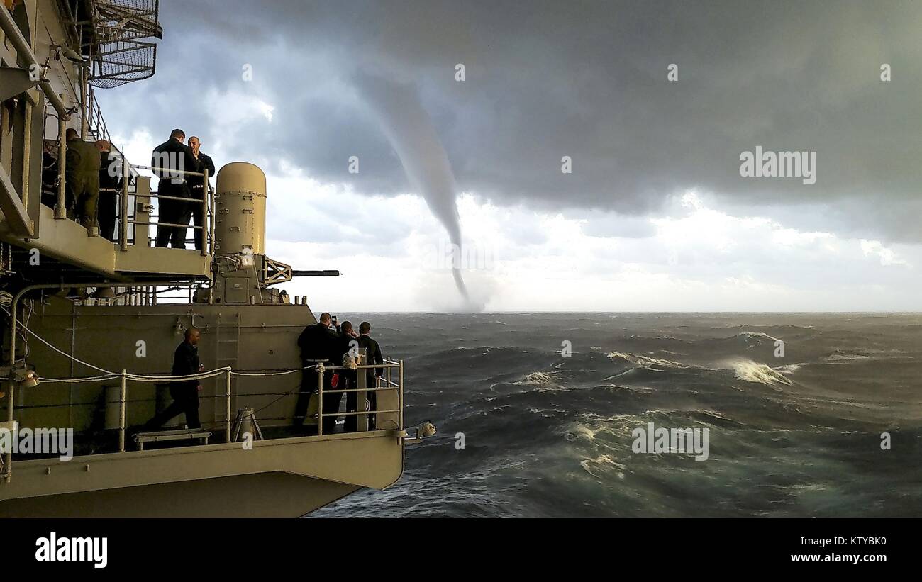 A waterspout forms in front of the U.S. Navy Gerald R. Ford-class aircraft carrier USS Gerald R. Ford December 4, 2017 in the Atlantic Ocean. Stock Photo