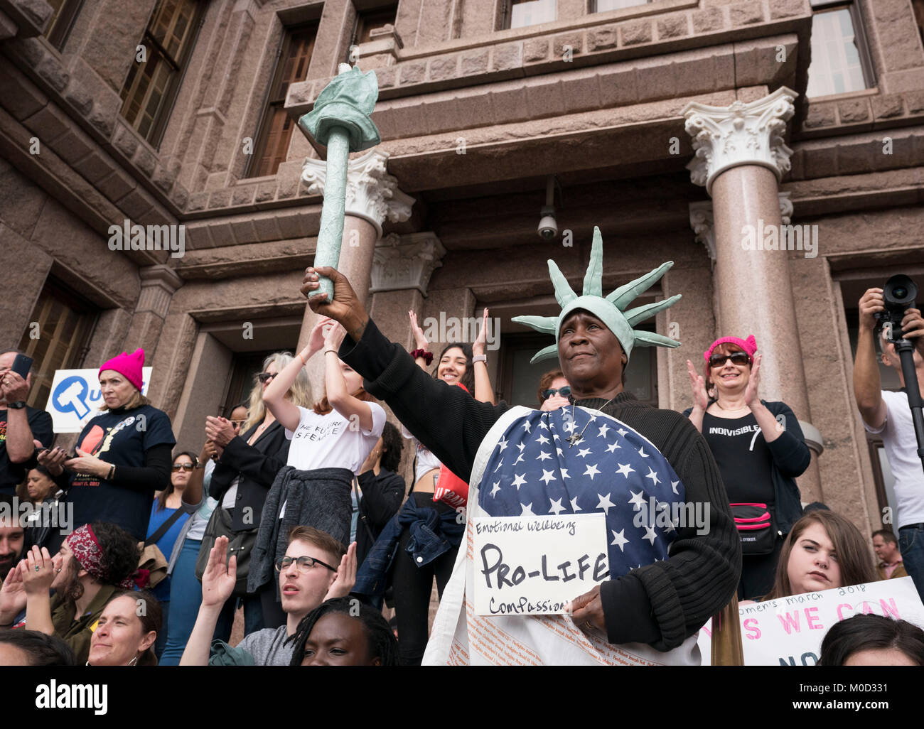 Peace Costanzo, a daily visitor to the Texas Capitol in her Statue of Liberty-like costume, stands on the Capitol steps surrounded by protesters  during a women's rights rally commemorating the anniversary of last year's Women's March on Washington and Pres. Donald Trump's controversial first year in office. Stock Photo