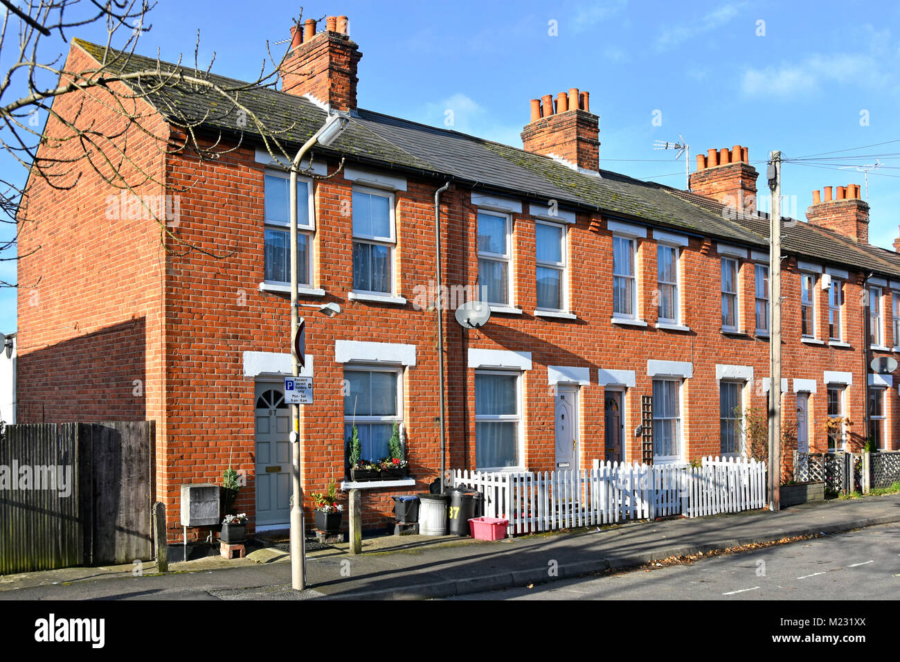 Terraced houses in residential street of red brick homes permit parking restriction sign and very small front garden space Brentwood Essex England UK Stock Photo