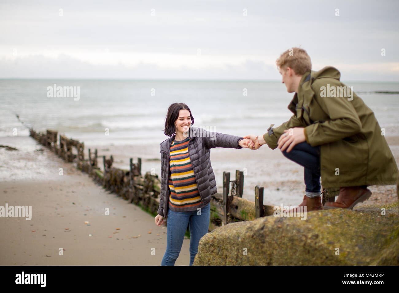 Boyfriend helping girlfriend climb a rock Stock Photo