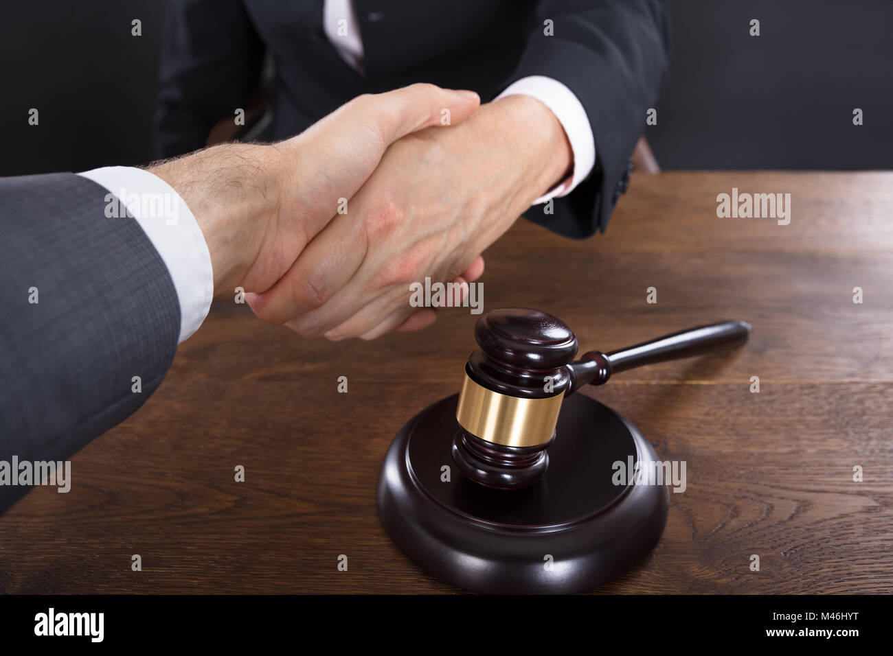 Close-up Of A Client And Judge Shaking Hands With Each Other Near Gavel Stock Photo