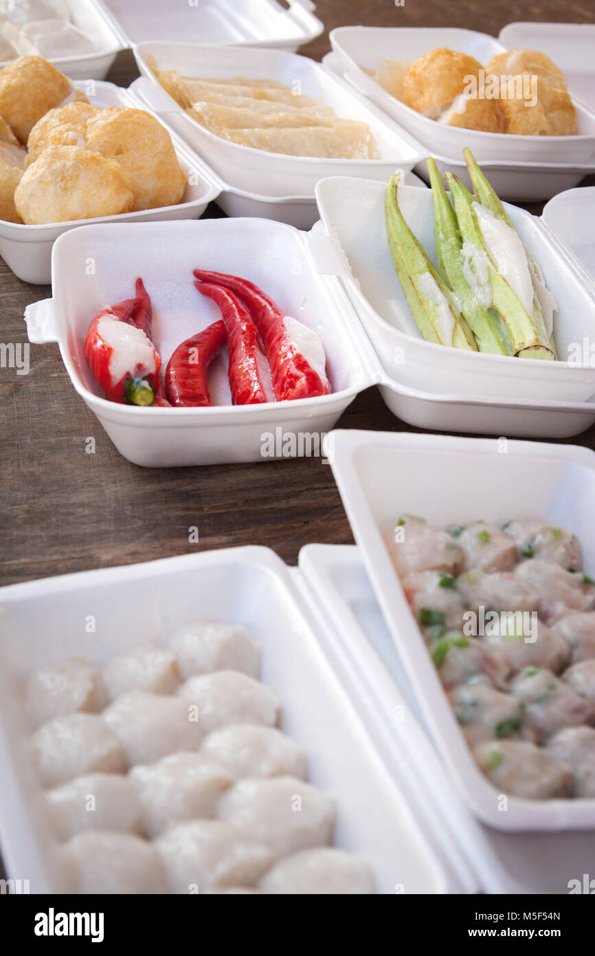 Fast food or takeaway food on a street food stall in Malaysia. Pre-packed in polystyrene trays ready for the lunch break. Red chillies, Okra and Bakso Stock Photo