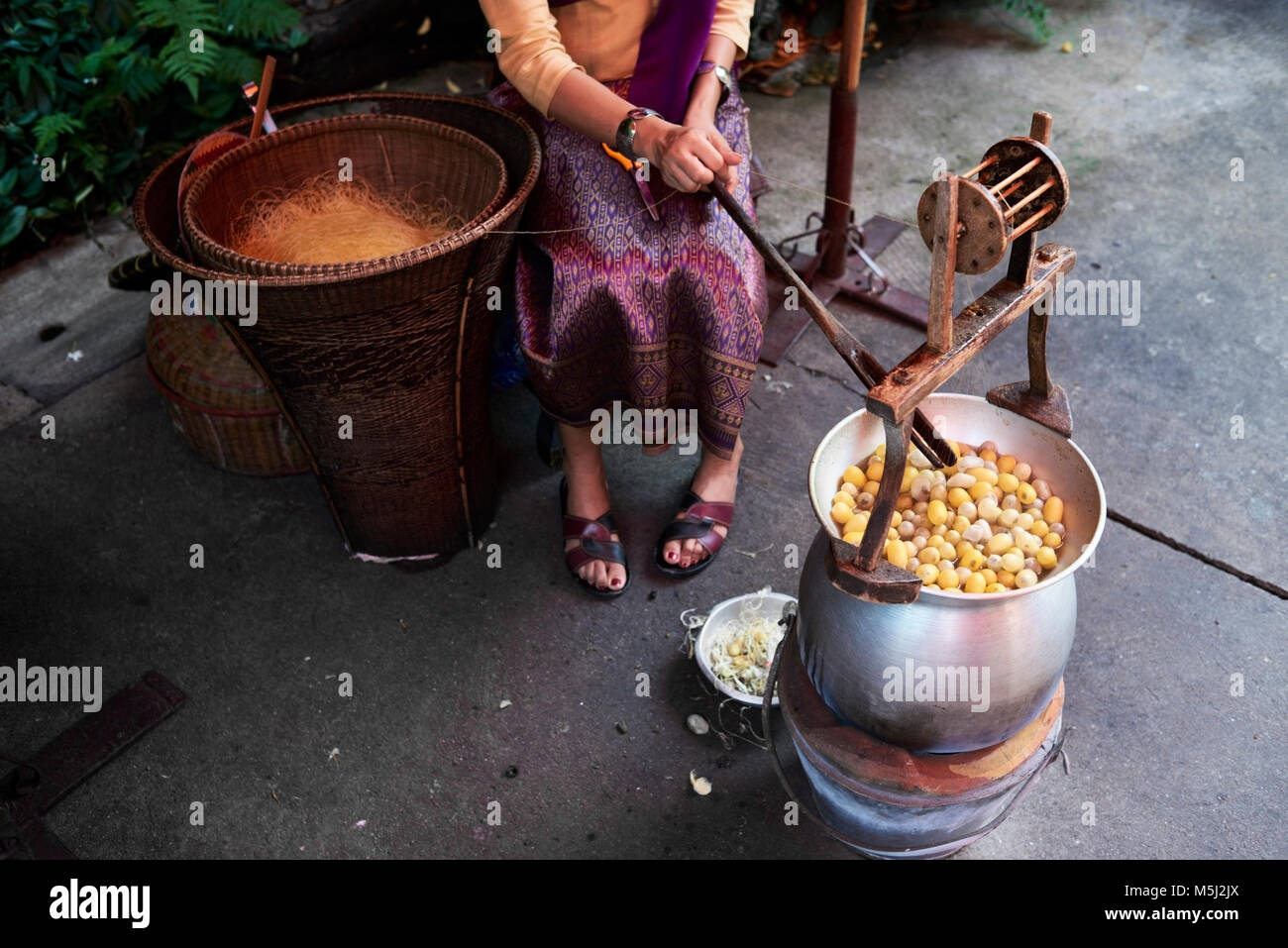 Traditional silk maker outdoors in the process of making silk fiber, Bangkok Thailand. Stock Photo