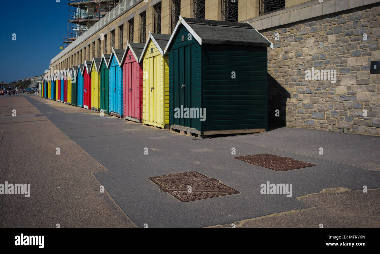 A line of multi coloured colourful locked and empty beach huts at Boscombe part of Bournemouth beach in Dorset England. Stock Photo