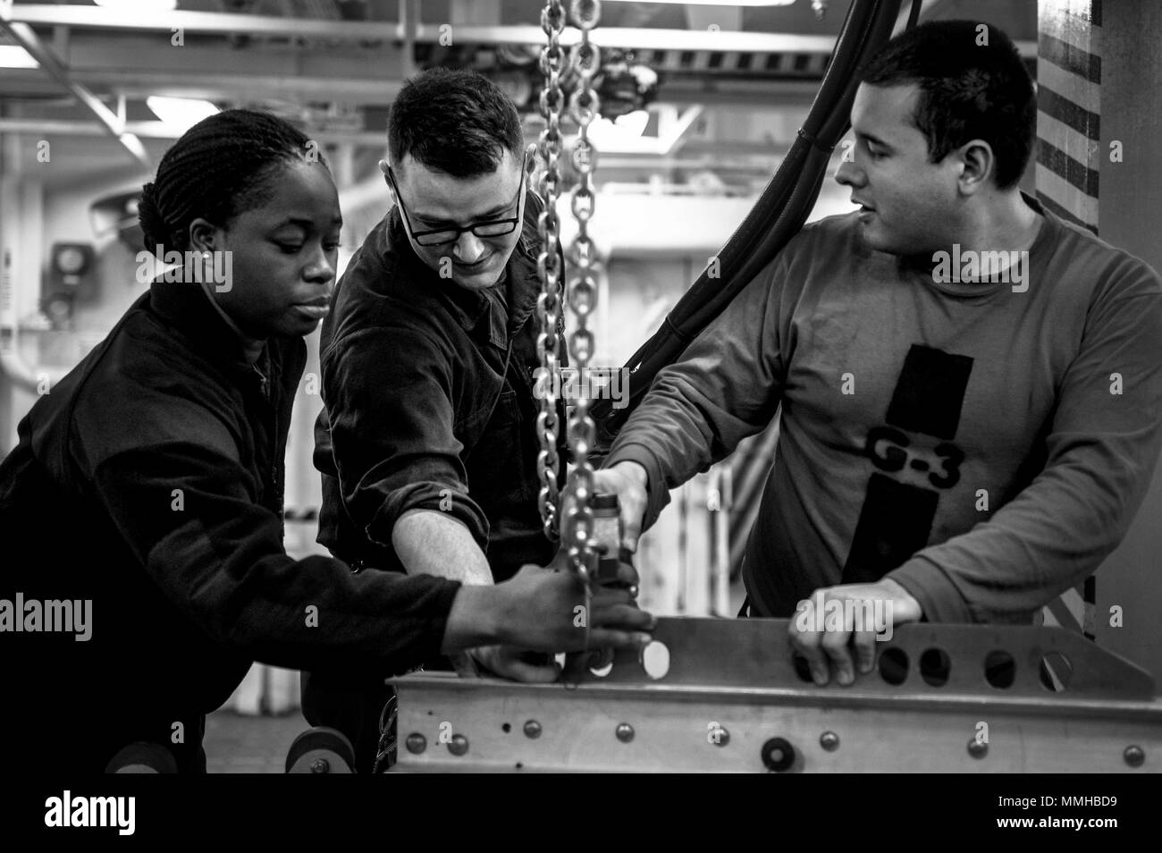 180510-N-SO730-0058 ATLANTIC OCEAN (May 10, 2018) Left to right, Aviation Ordnanceman 3rd Class Amber Davis, from Birmingham, Alabama, Aviation Ordnanceman Airman William Thompson, from Erie, Pennsylvania, and Aviation Ordnanceman Airman Jacob Lane, from Atascadero, California, get a crane situated for a simulated bomb building with the French navy aboard the aircraft carrier USS George H.W. Bush (CVN 77), May 10, 2018. The ship is underway in the Atlantic Ocean conducting carrier air wing exercises with the French navy to strengthen partnerships and deepen interoperability between the two nat Stock Photo