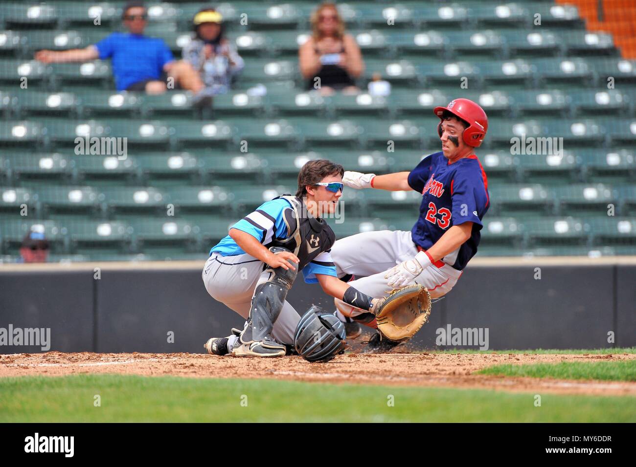 Runner scoring as the opposing catcher awaits a tardy throw from the outfield. USA. Stock Photo