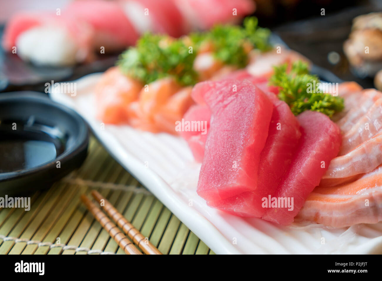 Mixed sliced fish sashimi in white plate. Sashimi Salmon and Tuna set with Tuna, flying fish roe caviar and Foie Gras closeup. Japan restaurant menu Stock Photo