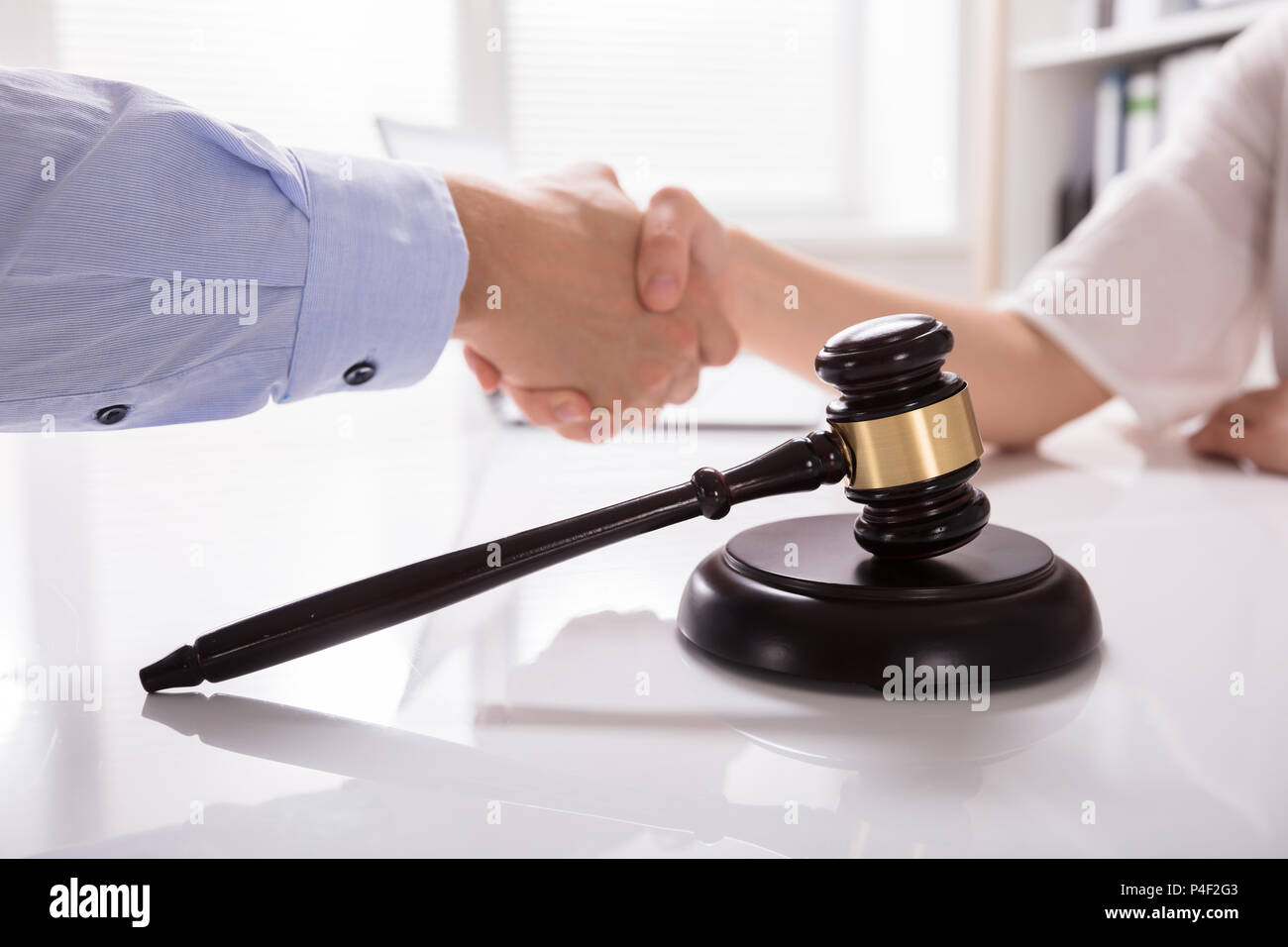 Close-up Of Mallet In Front Of Judge Shaking Hands With His Client Stock Photo