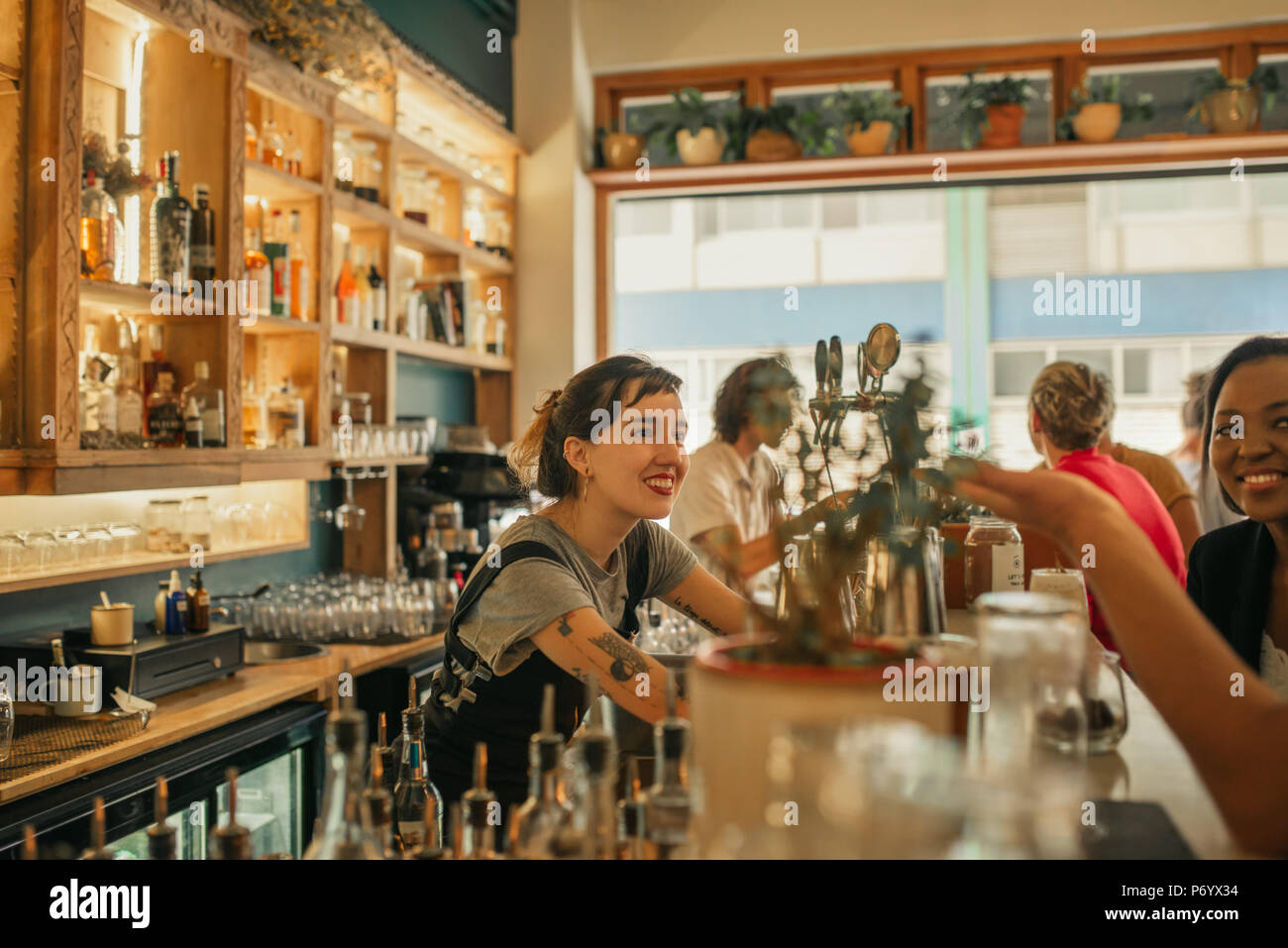 Smiling female bartender talking with customers at a bar counter Stock Photo