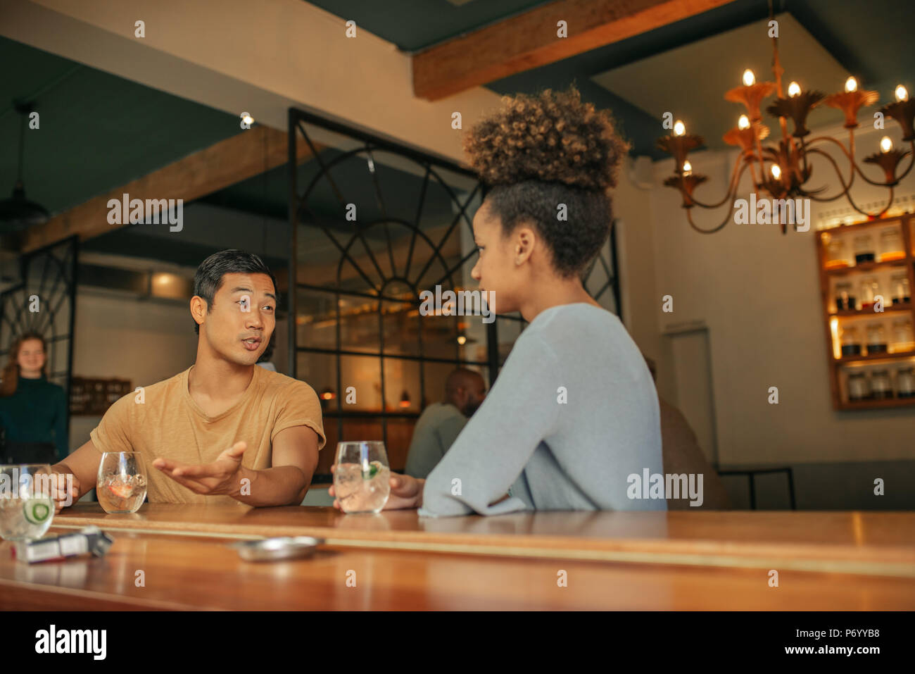 Friends sitting at a bar couner enjoying drinks together Stock Photo