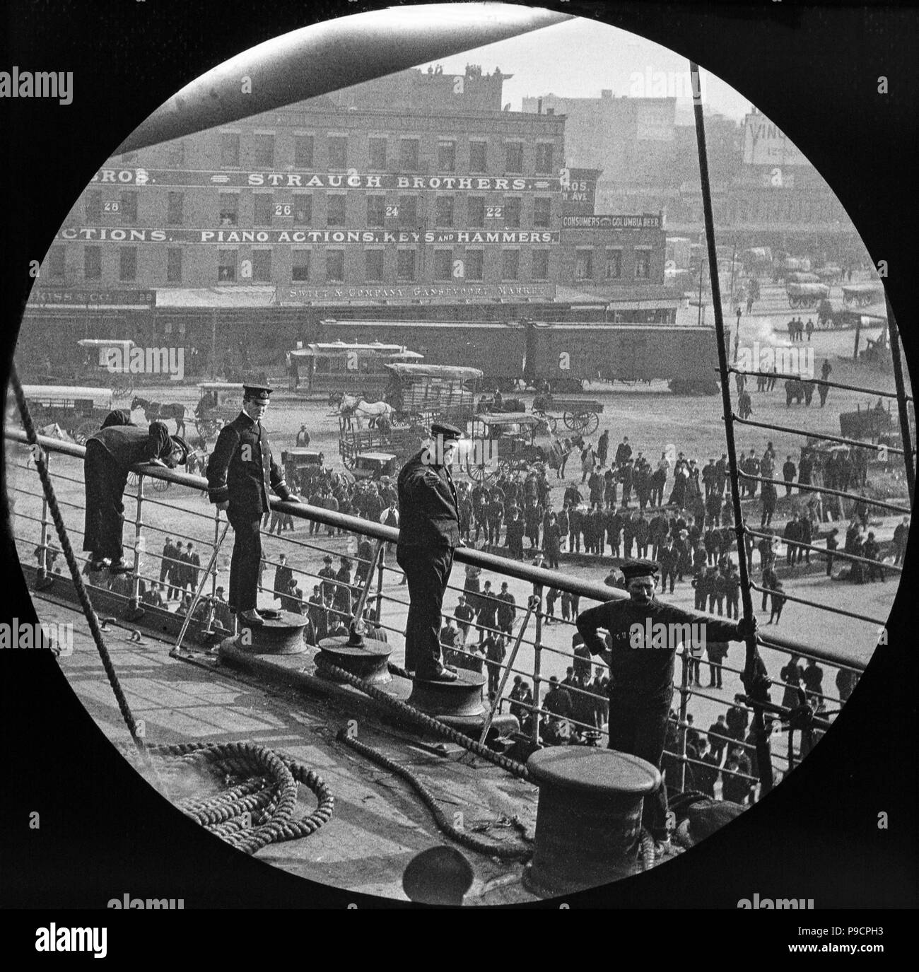 Photo of some officers and crew aboard a Cunard Ocean Liner in dock in New York, late 19th or early 20th century. The Starch Brothers building in there background. Stock Photo