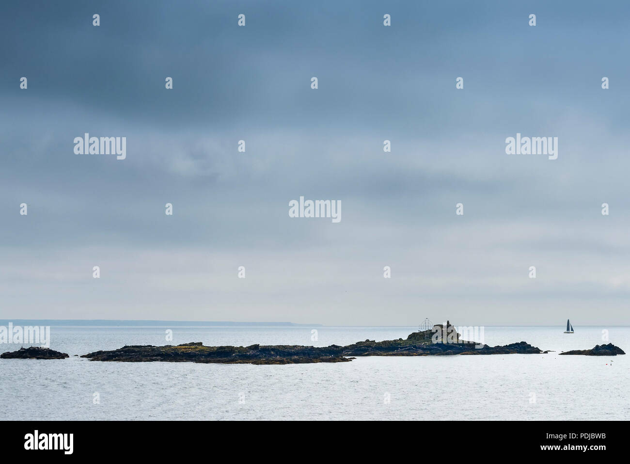 The small rocky reef known as St Clements Isle off the entrance to Mousehole Harbour in Cornwall. Stock Photo