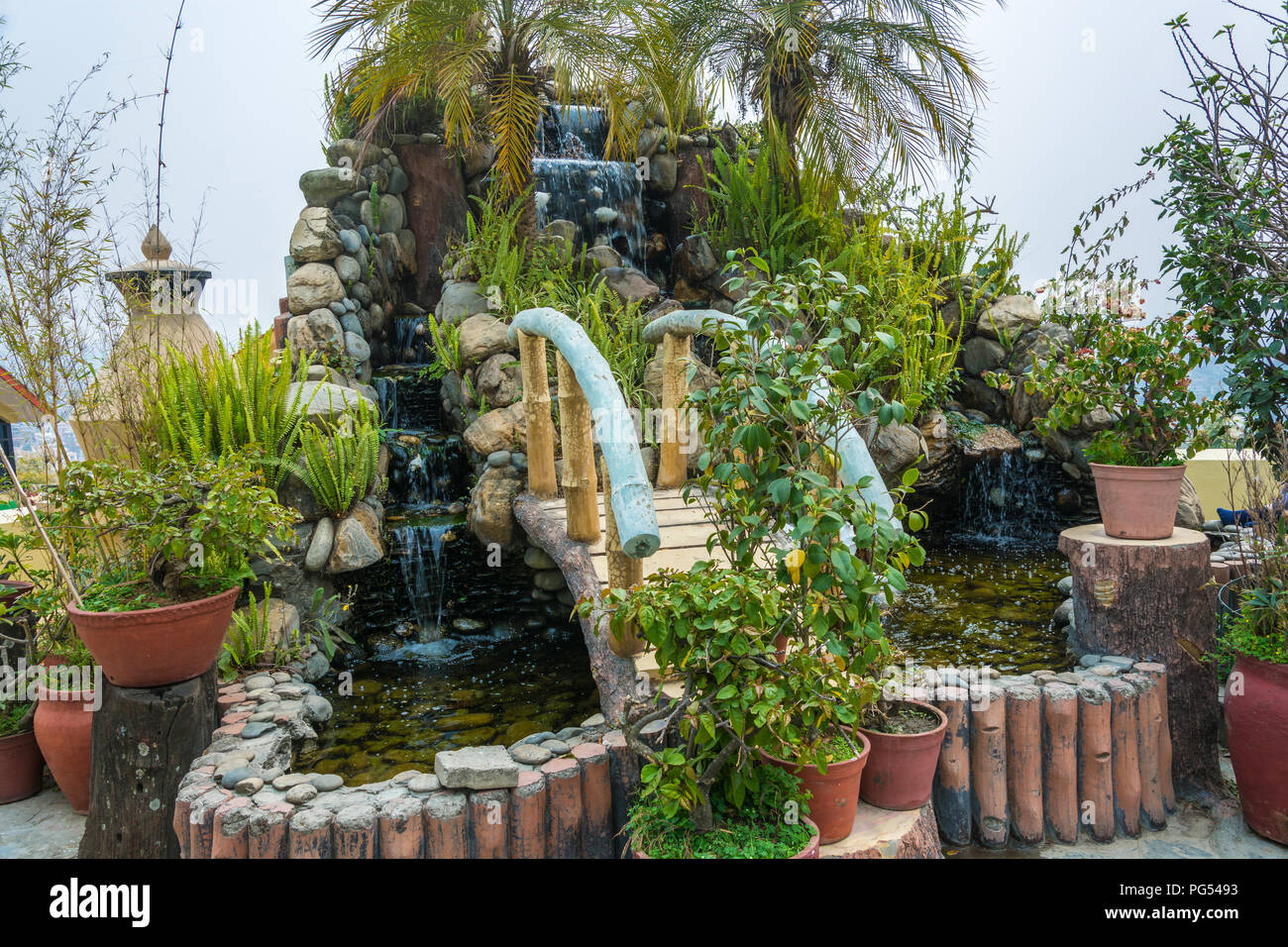 Man-made waterfall with a small bridge in the Park of the Buddhist monastery Kopan, Kathmandu, Nepal. Stock Photo