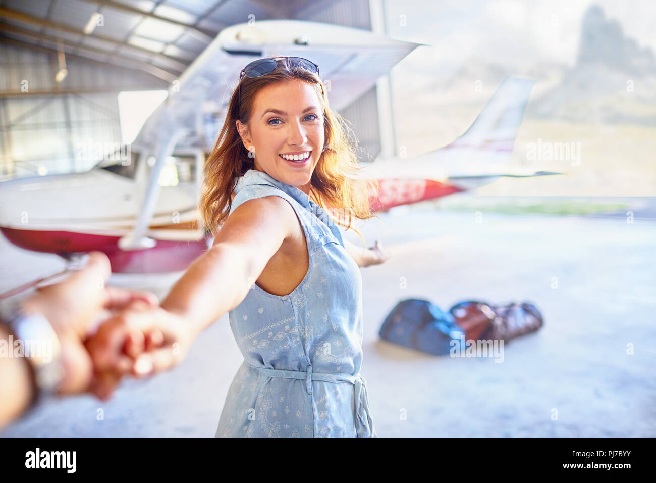 Personal perspective eager woman leading man by the hand toward small airplane Stock Photo