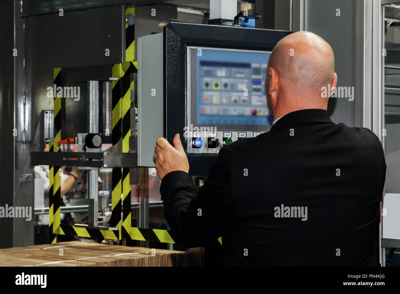 factory engineer controlling and pressing important technology button at control panel of an automatic machine in the manufacturing. Stock Photo