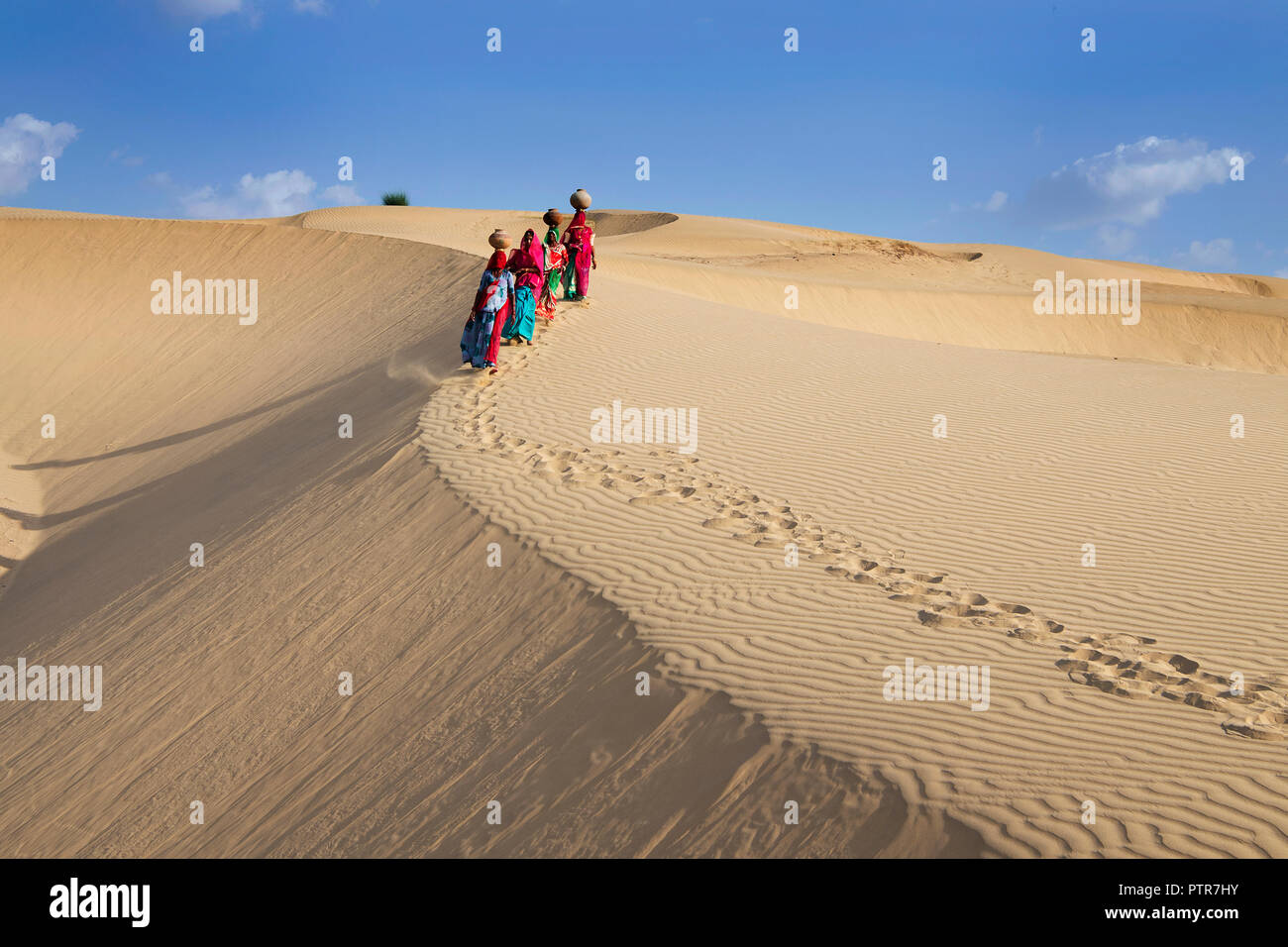 The image of Rajasthani traditional ladies with pots  in sand dunes of  Jaisalmer, Rajasthan, India Stock Photo