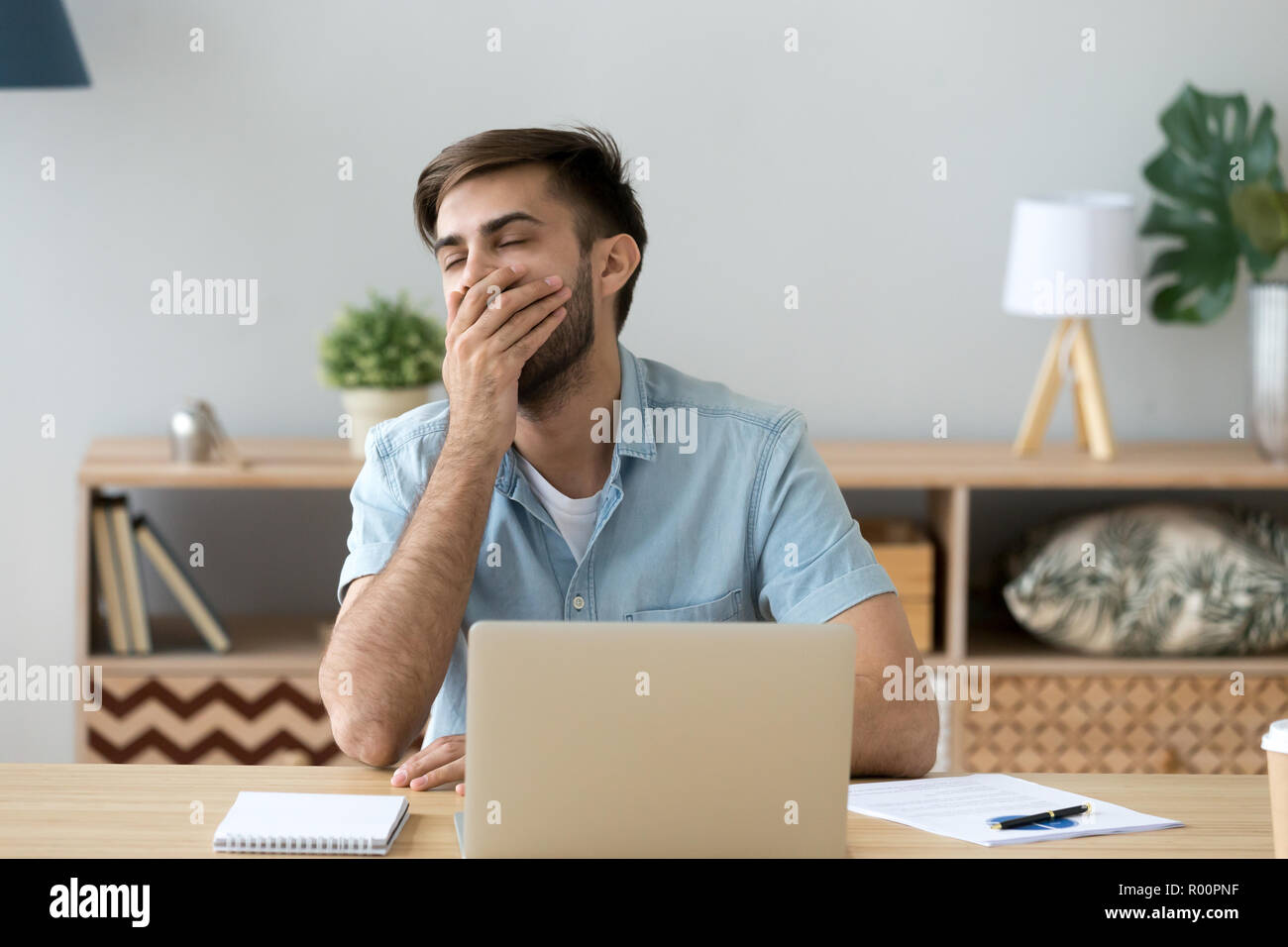 Bored young man sitting at the desk  Stock Photo