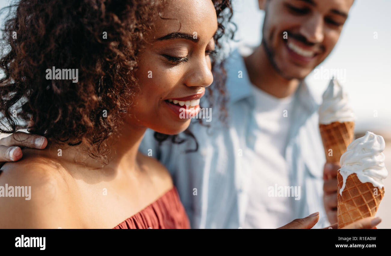 Smiling couple eating ice cream cone standing outdoors. Romantic couple enjoying ice cream. Stock Photo