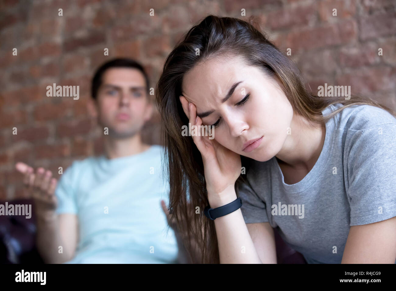 Offended man and woman are seated separately on sofa. Stock Photo