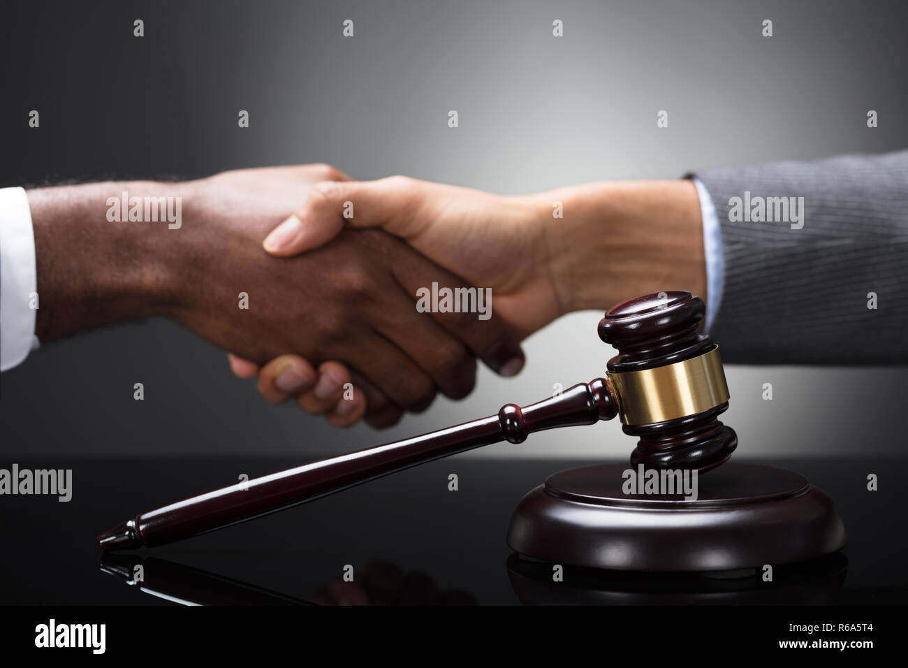 Mallet And Gavel In Front Of Two Businesspeople Shaking Hands Stock Photo