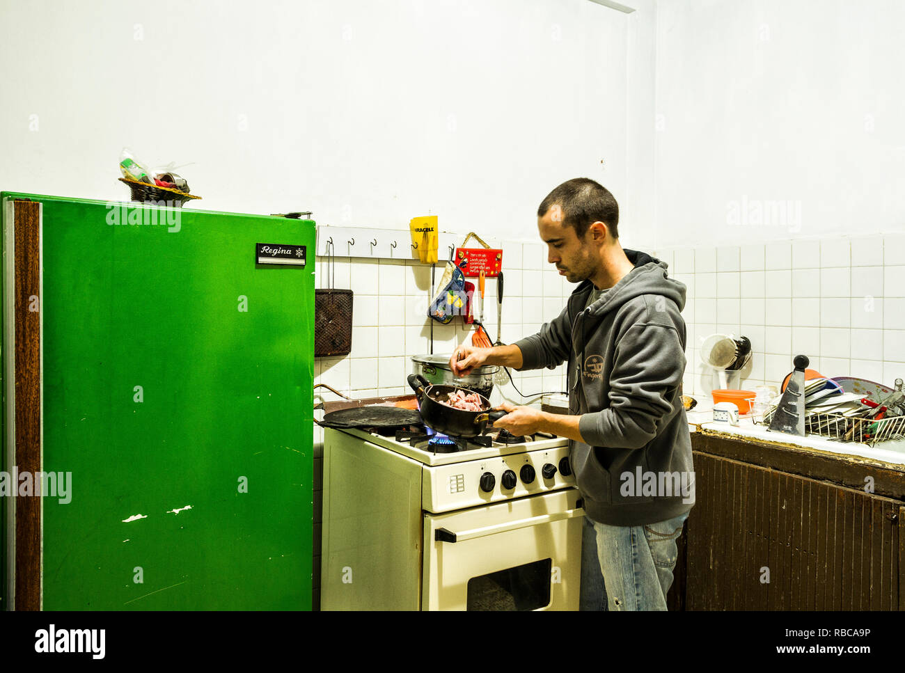 Man cooking in a hostel kitchen. Merida, Merida, Venezuela. Stock Photo