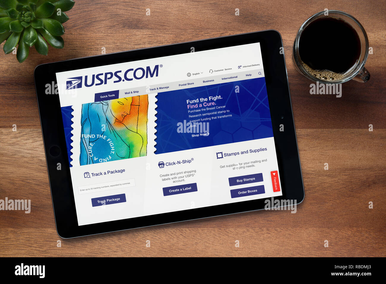 The website of USPS (United States Postal Service) is seen on an iPad tablet, resting on a wooden table (Editorial use only). Stock Photo