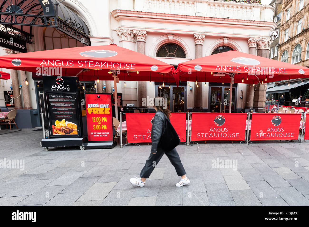 London, UK - September 12, 2018: Angus Steakhouse red restaurant by Queen's House building in Leicester Square during day in city with person walking Stock Photo