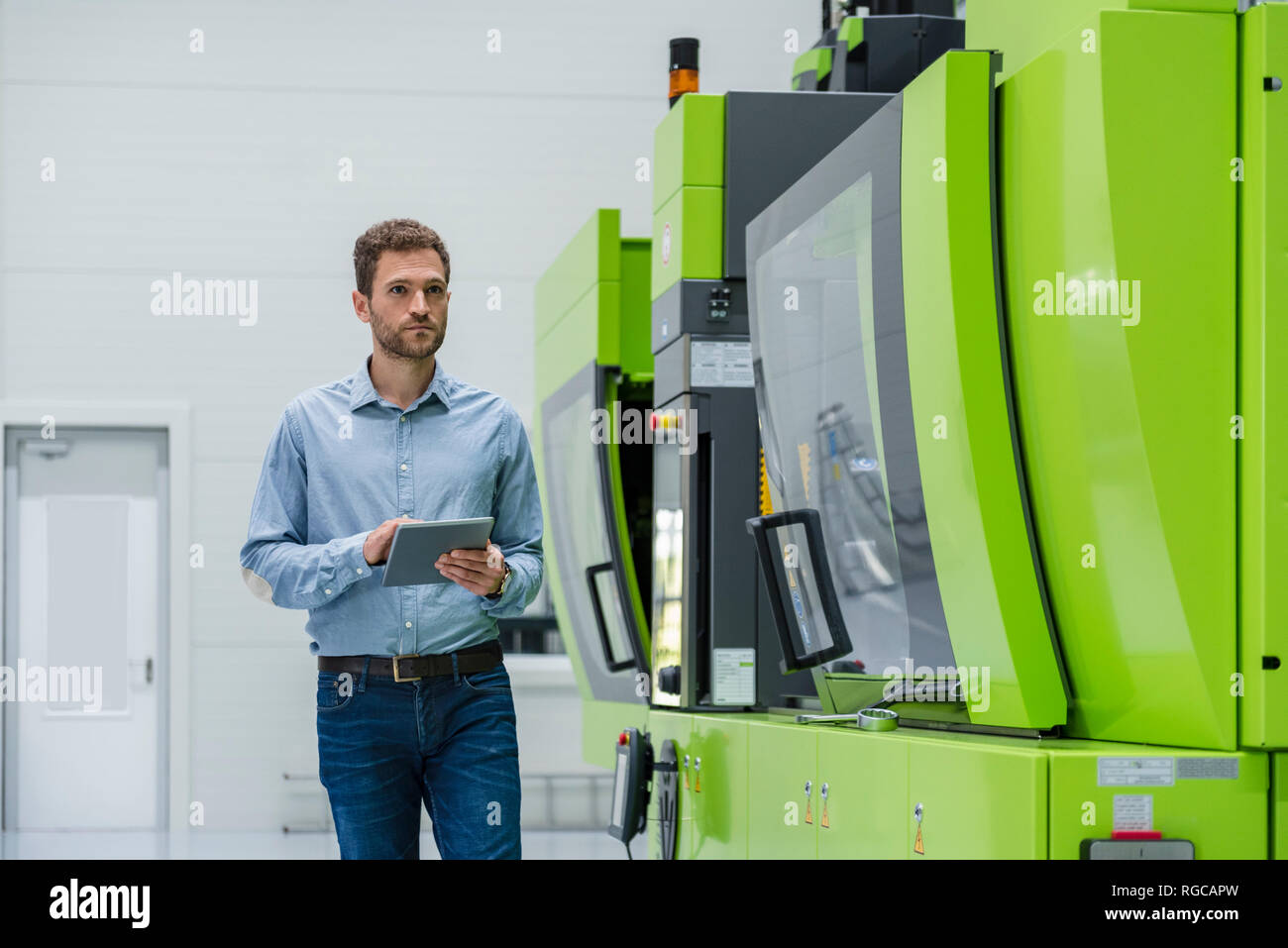 Businessman in high tech company controlling manufacturing machines, using digital tablet Stock Photo