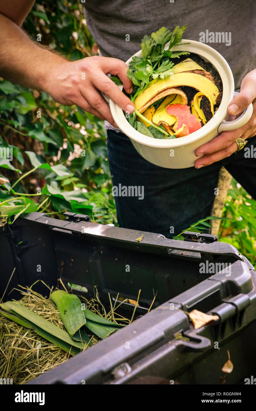 Mature man discarding kitchen scraps on compost pile Stock Photo