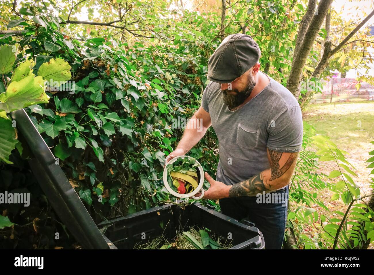 Mature man discarding kitchen scraps on compost pile Stock Photo