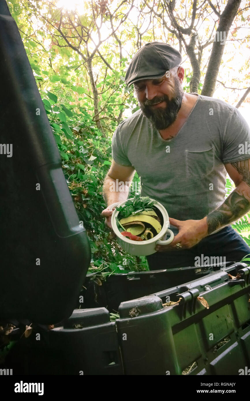 Mature man discarding kitchen scraps on compost pile Stock Photo