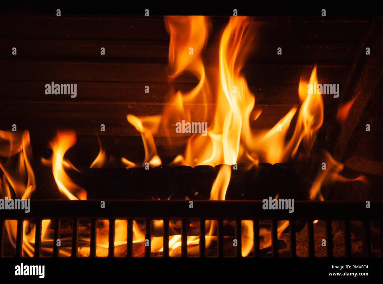 Firewood burns in the fireplace with a bright flame, close-up photo with selective focus Stock Photo