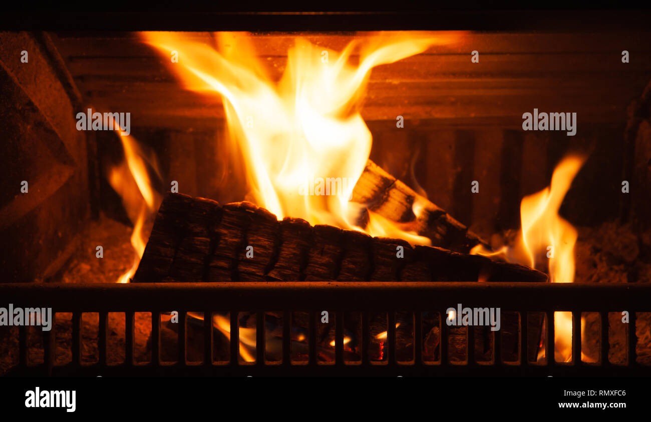 Firewood burns in the fireplace with a bright flame at night Stock Photo