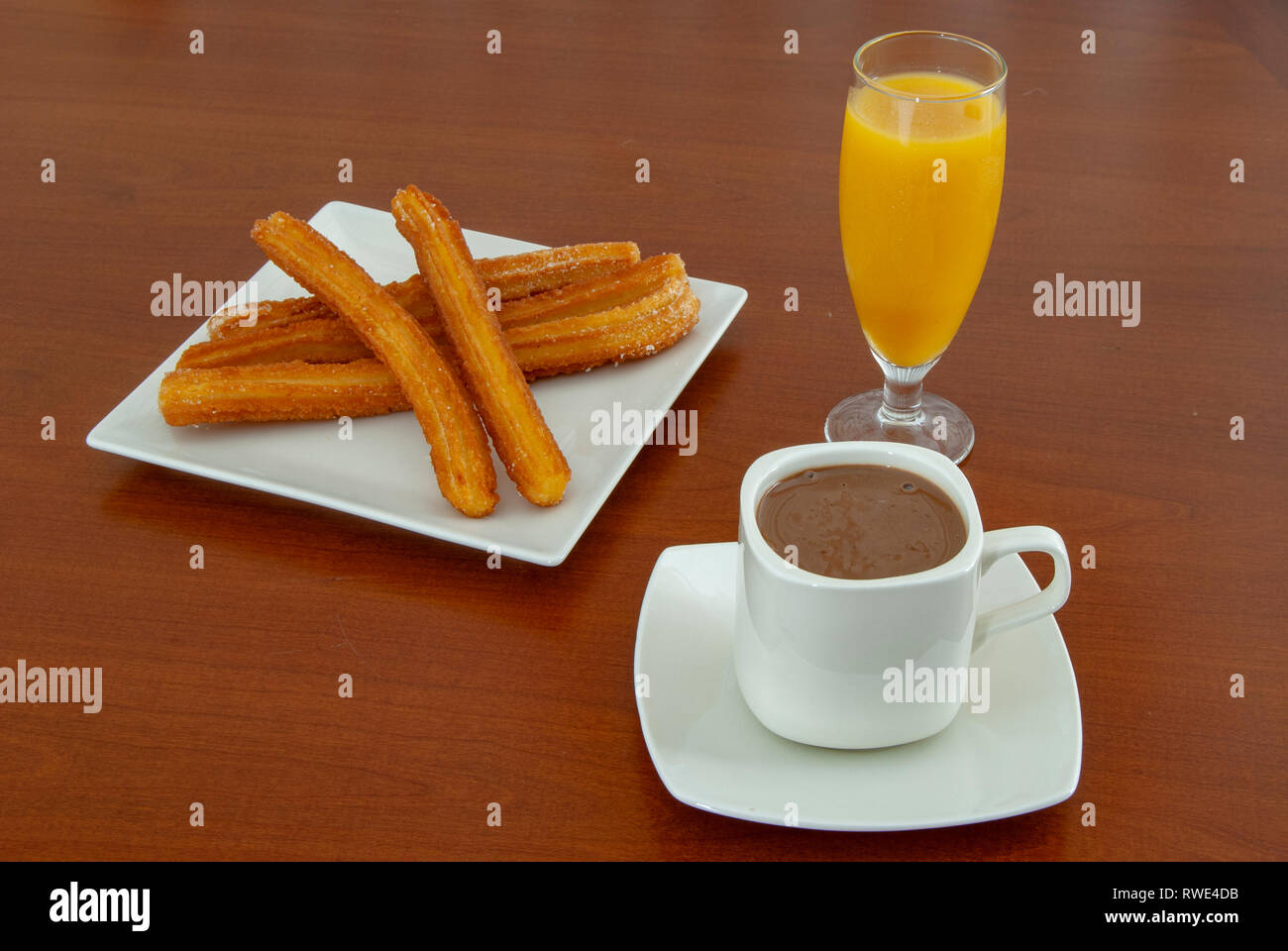 Traditional spanish churros with hot chocolate sauce  and orange juice, on a wooden table Stock Photo