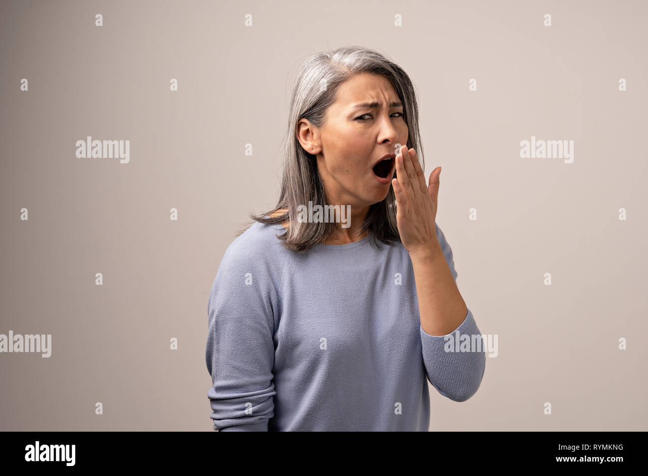 Tired Asian woman yawning in photo studio Stock Photo