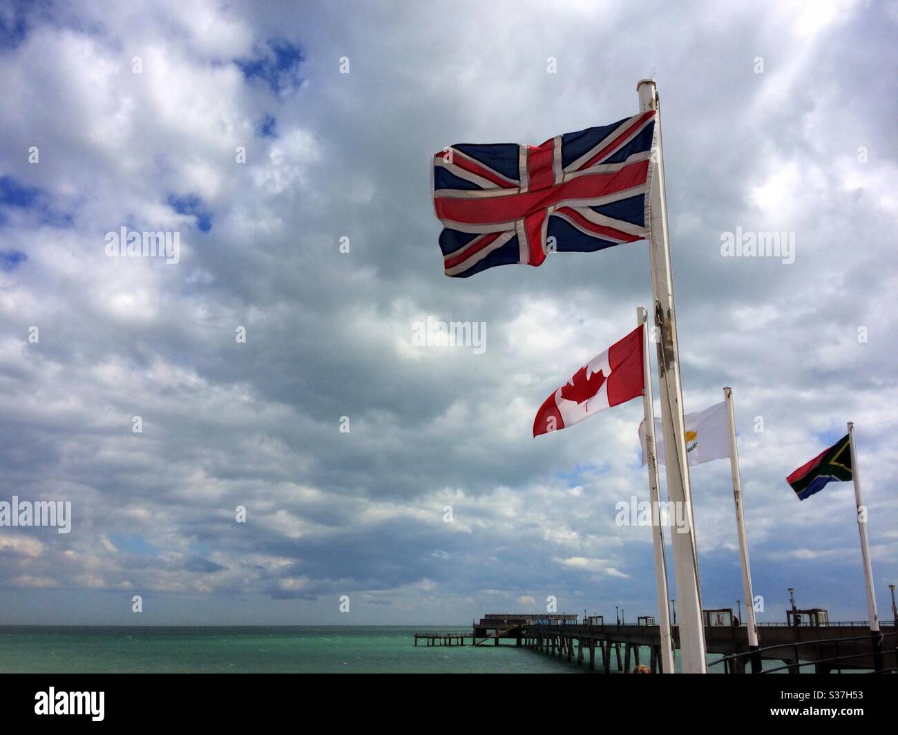 The Union Jack, Canadian & South African flags flying at the entrance to the pier at Deal Kent UK Stock Photo