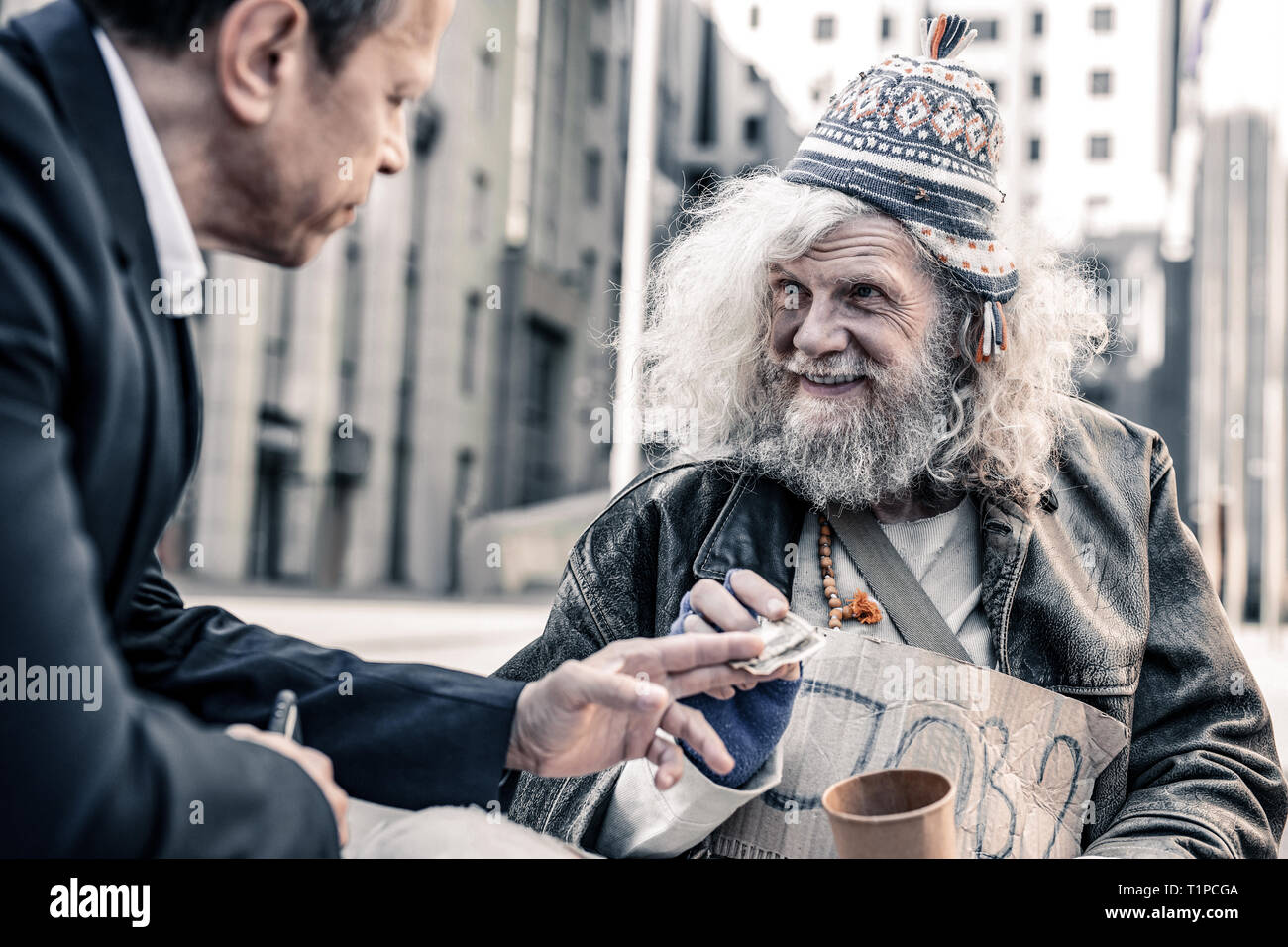 Beaming impressed grey-haired poor man thankfully receiving money Stock Photo