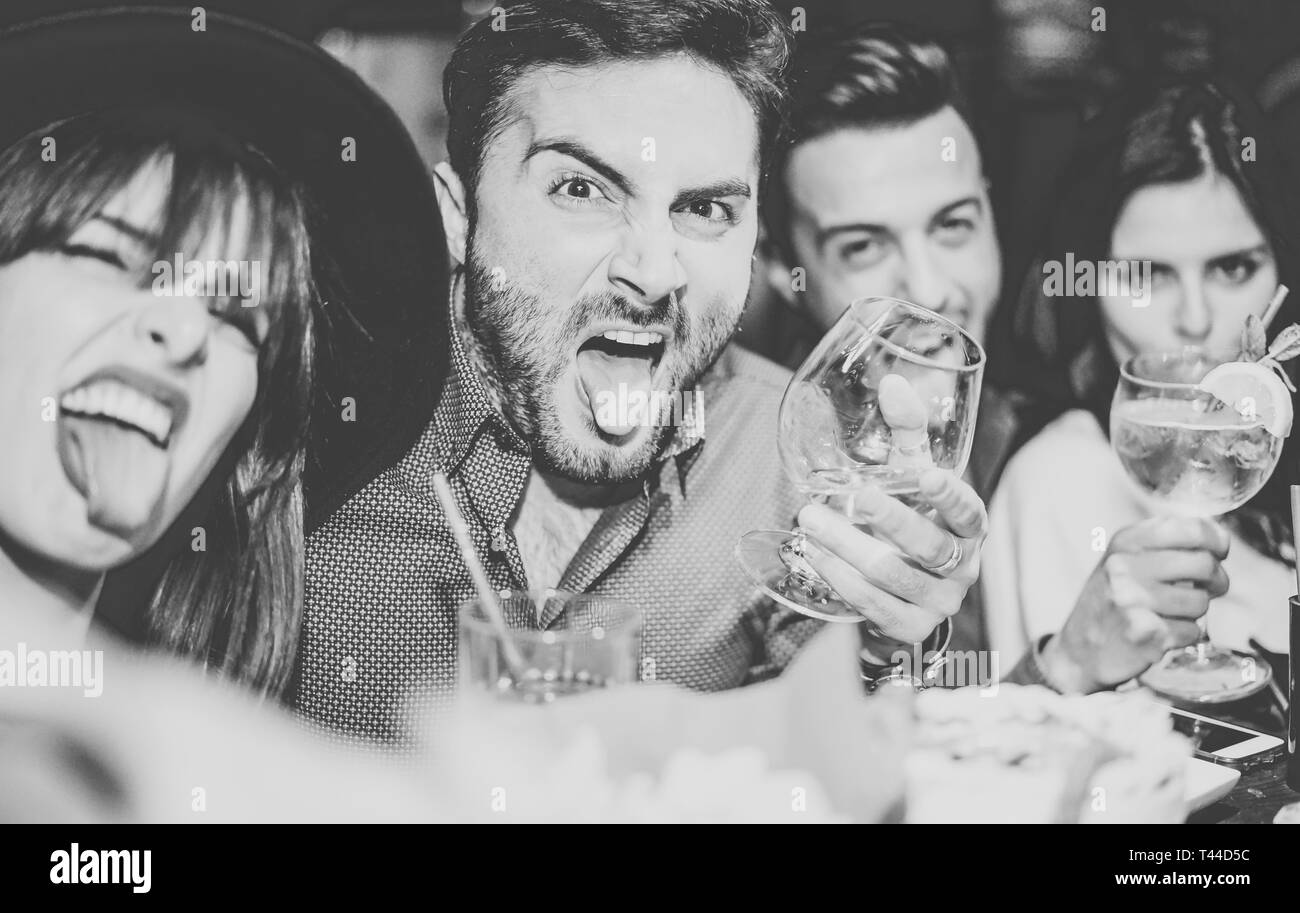 Friends having fun drinking cocktails and taking selfie in the bar - Young people taking photo in the club making silly faces Stock Photo