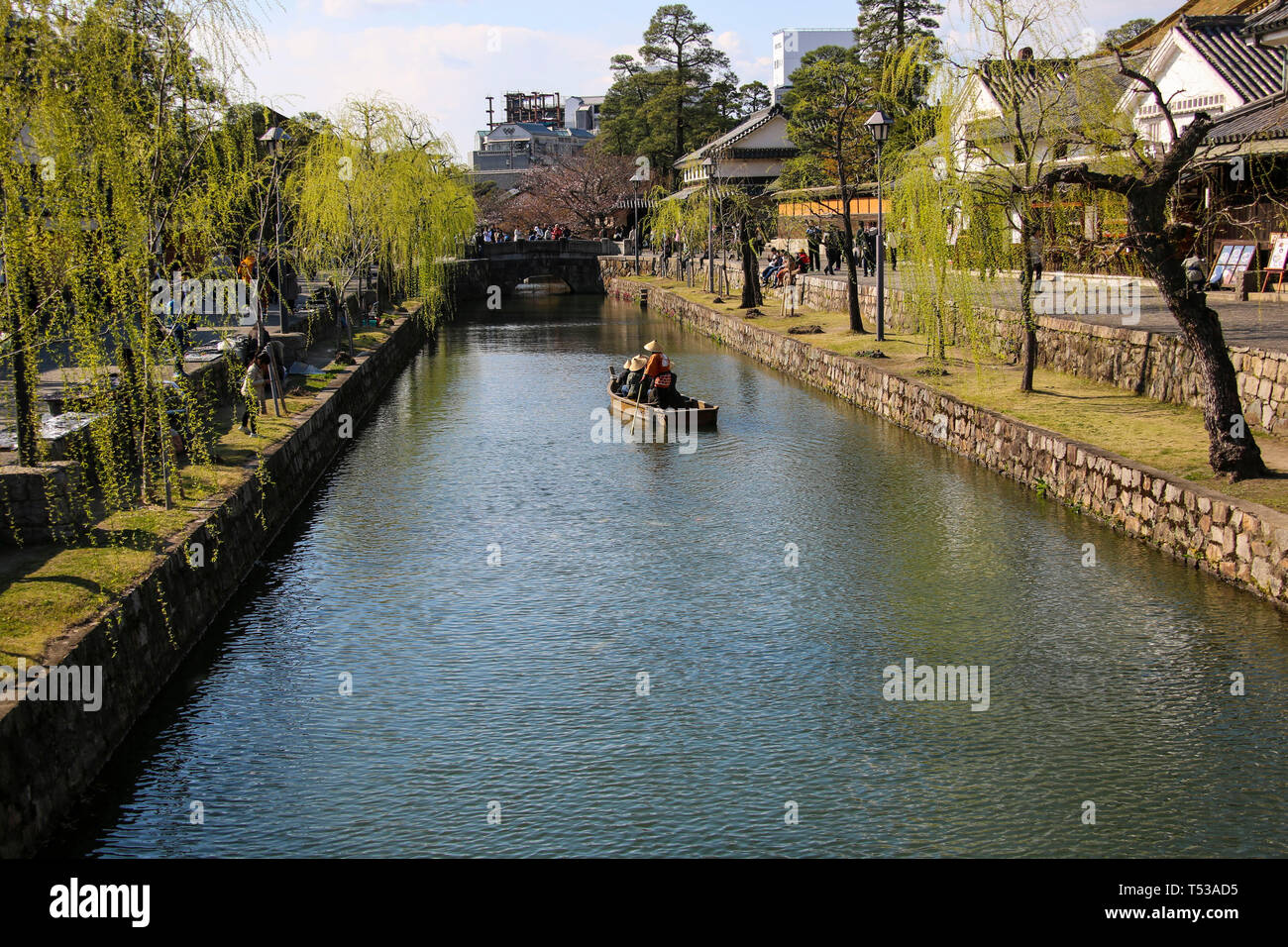 KURASHIKI, JAPAN - MARCH 31, 2019: Tourists are enjoying the old-fashioned boat along the Kurashiki canal in Bikan district of Kurashiki city, Japan. Stock Photo