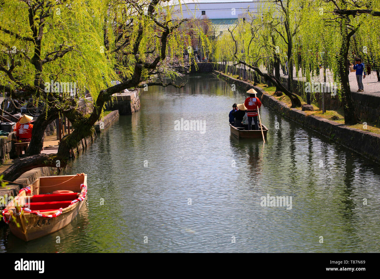 KURASHIKI, JAPAN - MARCH 31, 2019: Tourists are enjoying the old-fashioned boat along the Kurashiki canal Stock Photo