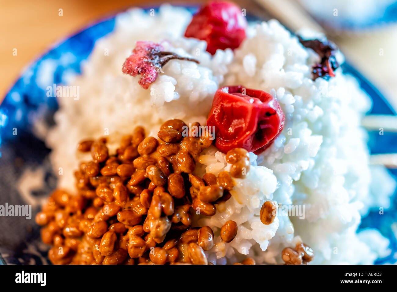 Traditional japanese dish plate in restaurant or home with, umeboshi and salted sakura flowers and fermented natto soybeans on pile of rice Stock Photo