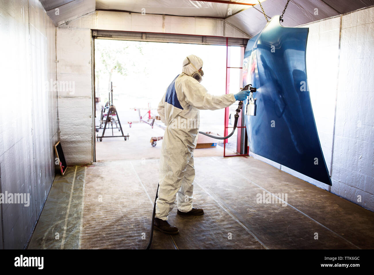 Mechanic painting vehicle part at auto body shop Stock Photo